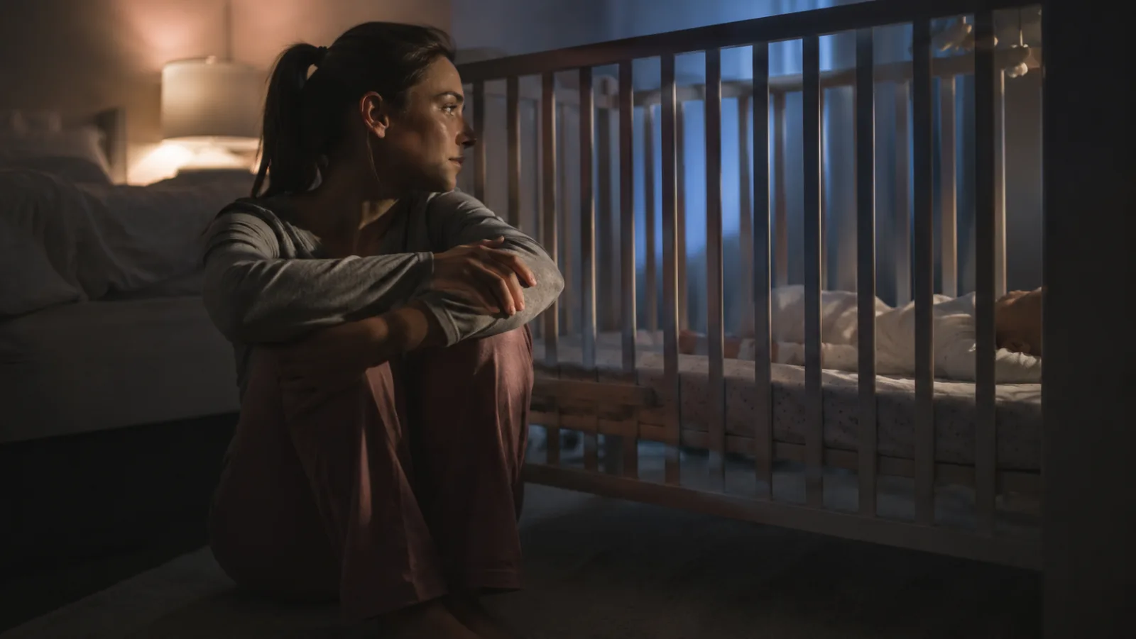Mãe sentada ao lado do berço de madrugada